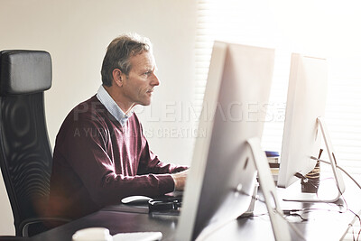 Buy stock photo A businessman using a computer in a modern office. A mature male executive working online for business at his desk