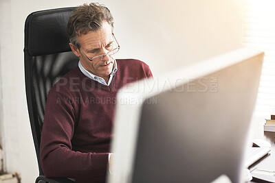Buy stock photo A businessman using a computer in a modern office. A mature male executive working online for business at his desk