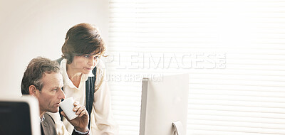 Buy stock photo Two colleagues using a computer in a modern office. A mature businessman and businesswoman working online, talking about business matters