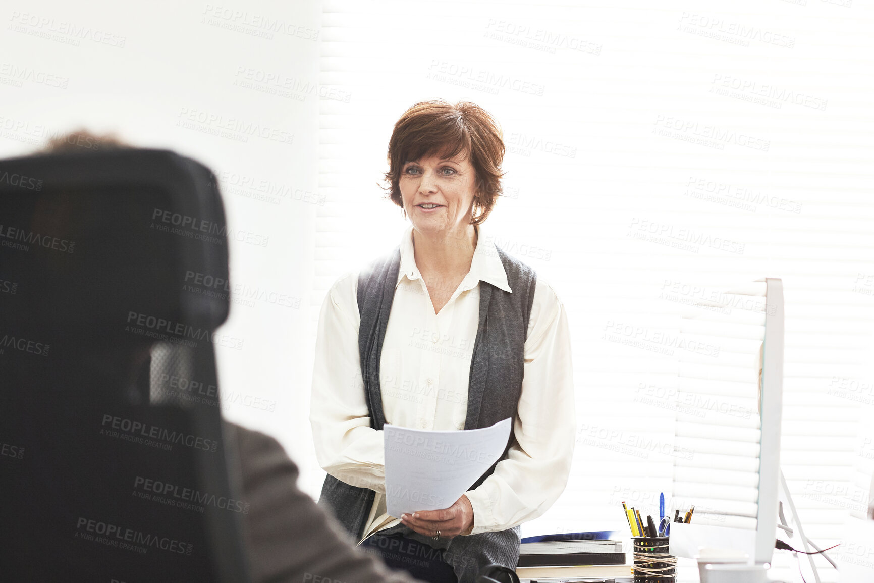 Buy stock photo Two colleagues talking finance in a modern office. A mature businessman and businesswoman working with paperwork, discussing business matters