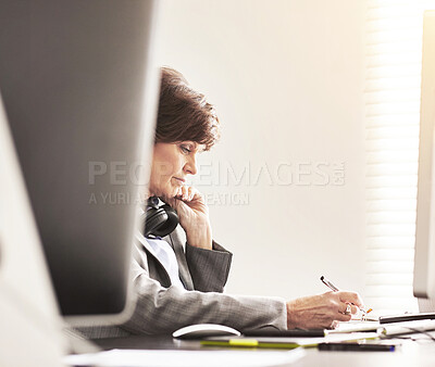 Buy stock photo A businesswoman using a computer and writing a note in a modern office. A mature female executive working online for business at her desk