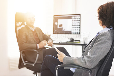Buy stock photo Two colleagues using a tablet in a modern office. A mature businessman and businesswoman working online with a touchscreen, talking about business matters