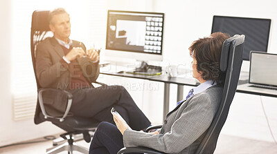 Buy stock photo Two colleagues using a tablet in a modern office. A mature businessman and businesswoman working online with a touchscreen, talking about business matters