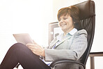 A businesswoman using a digital tablet in a modern office. A mature female executive browsing online for business with a touchscreen at work