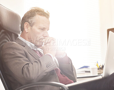 Buy stock photo A businessman using a laptop in a modern office. A mature male executive browsing online for business with a computer at work