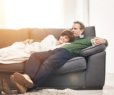 Buy stock photo A mature couple relaxing at home. A happy senior man and woman in love, having a coffee or tea break, sharing a cosy moment on the couch