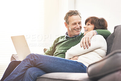 Buy stock photo A mature couple using a laptop, relaxing at home. A happy senior man and woman in love browsing online with a computer on the couch