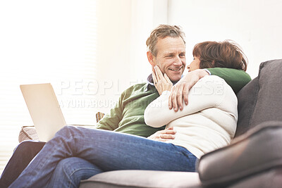 Buy stock photo A mature couple using a laptop, relaxing at home. A happy senior man and woman in love browsing online with a computer on the couch