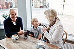 Happy family, grandparents and kid at cafe for conversation, talking of holiday and visit in London. Senior people with boy or child at coffee shop for discussion, funny chat and planning at table