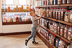 Boy child, jar and candy in shop for gift, present and choice with thinking, dessert and sugar treat. Customer, kid and retail store with container for sweets sale, decision and shopping for discount