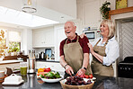 Funny, laugh and senior couple cooking in kitchen with care, joke and support at home. Health, food and happy people with love in a house for brunch, salad or meal prep with tomatoes or funny humour