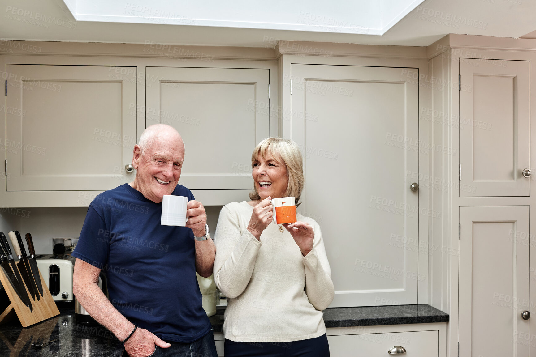 Buy stock photo Coffee, laughing and senior couple in kitchen at home together in the morning for conversation, love and healthy connection. Tea, funny and elderly man and woman enjoying drink in mug in retirement.