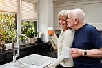 Kiss, senior couple and coffee in the morning for love, relax and bonding in retirement. House, happy and an elderly man with affection or care for a woman, tea or a drink together in the kitchen