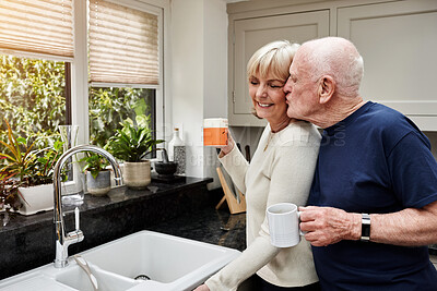 Buy stock photo Kiss, senior couple and coffee in the morning for love, relax and bonding in retirement. House, happy and an elderly man with affection or care for a woman, tea or a drink together in the kitchen