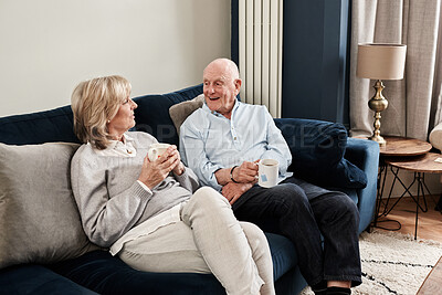 Buy stock photo Coffee, relax and retirement with a senior couple on a sofa in the living room of their home for conversation. Tea, smile or wellness with a happy elderly man and woman talking in their apartment