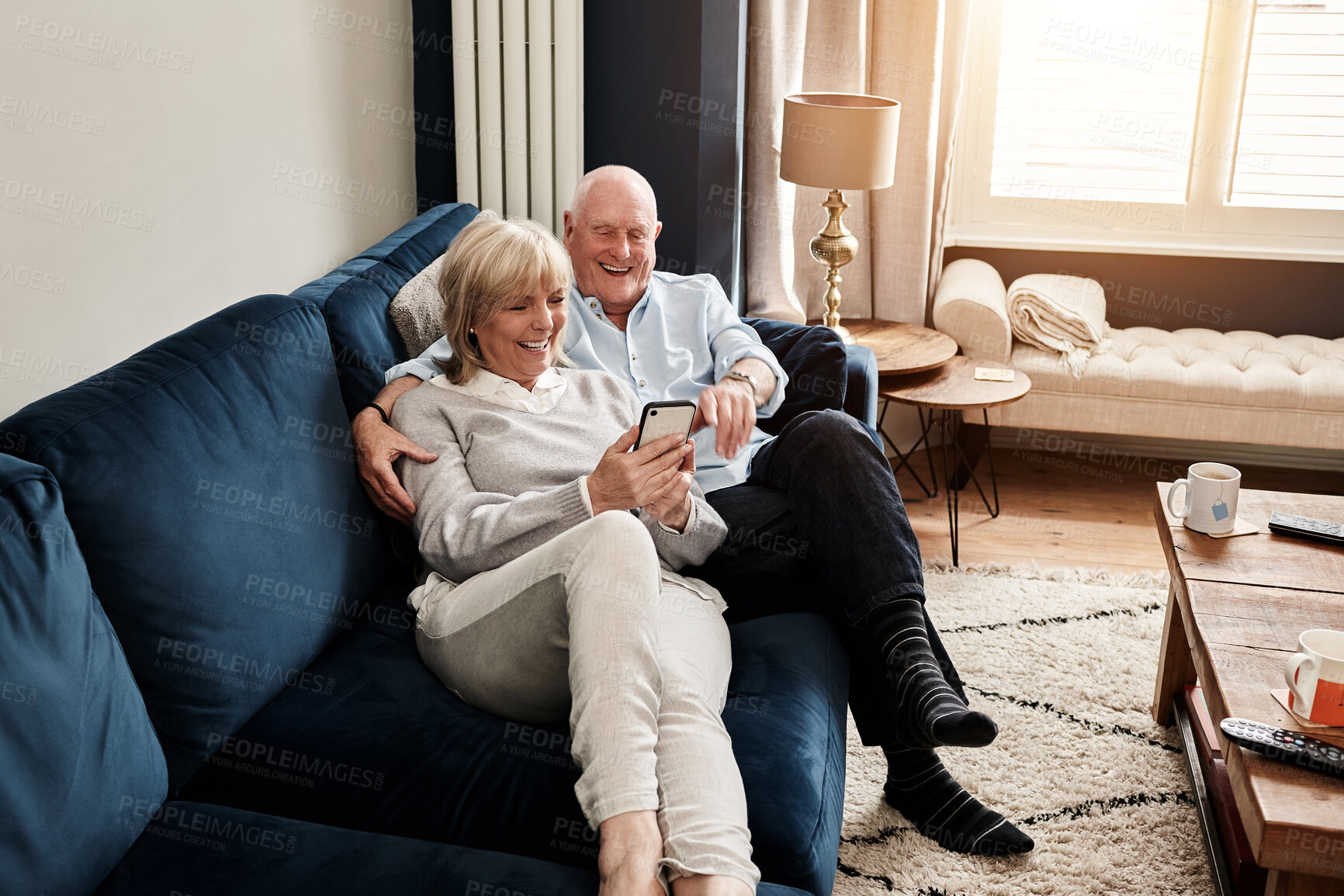 Buy stock photo Phone, relax and retirement with a senior couple on a sofa in the living room of their home for conversation. Mobile, smile or wellness with a happy elderly man and woman talking in their apartment