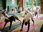 Group, people and stretching legs for yoga, workout and exercise in fitness centre or gym with mat. Wellness, men and woman with pilates, physical activity and training on floor of studio for balance
