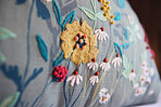 Home, decor and pillow or closeup upholstery of flowers in apartment or creative stitching, decorations or interior design. Cushion, floral and cozy environment or house, accommodation or hotel room