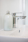 Bathroom, soap and dispenser at hotel for accommodation with cleaning equipment at resort. Closeup of interior, sink tap or faucet with container, bottle or domestic decor of toiletries at home