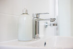 Bathroom, soap and faucet with dispenser at hotel for accommodation or cleaning equipment at resort. Closeup of interior, sink or tap with container, bottle or domestic decor of toiletries at home
