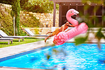 Man, flamingo and jump into pool for swim, luxury and enjoy the summer at resort. Pink float, male person and dive at water with inflatable toy, excitement and energy on weekend trip for vacation