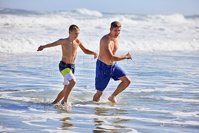 Buy stock photo Dad, boy and running at beach with waves, bonding or love in splash, vacation and together in nature. Father, child and playful with care, holiday or people with family in sunshine by ocean in Spain