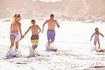 Parents, children and splash in water at beach for vacation, love or summer for running together in nature. Dad, child and playful with back, holiday or people with family in sunshine by sea in Spain