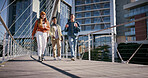 City, students and friends walking on bridge in city together with smile, coffee and conversation. University, scholarship and happy group of friends chat on morning commute to urban college campus
