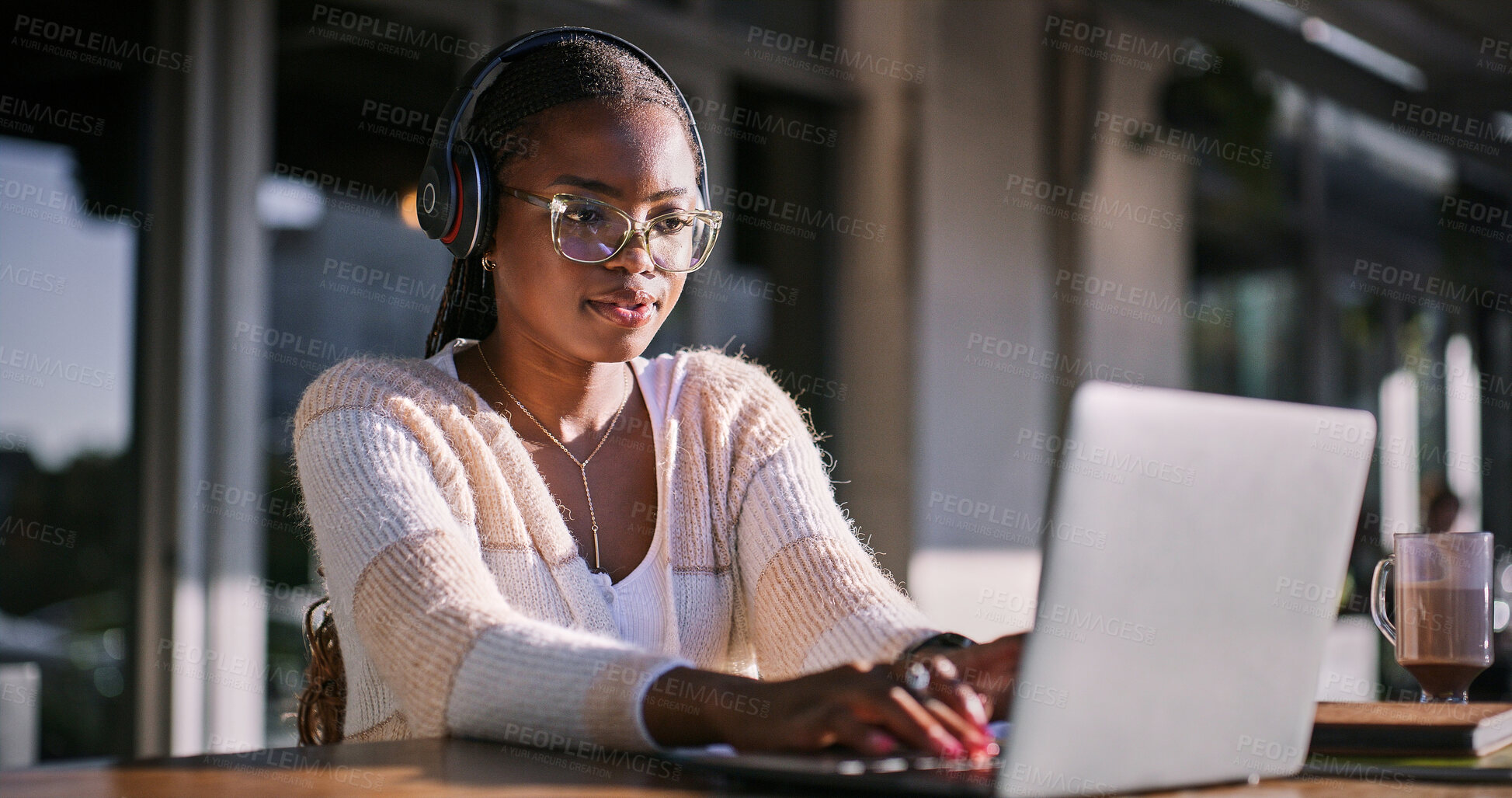 Buy stock photo Black woman, university student and cafe with laptop and headphone for assignment outdoor. Female person, college learner and audio for education with research or study for exam and assessment