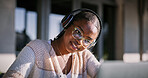Glasses, headphones and black woman with laptop, smile and listening to audio, video editing and creative. Outdoor, freelancer and content creation at cafe, sound and online for post production
