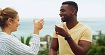 Travel, ocean and happy couple cheers at hotel for tropical vacation with love, relax or bonding. Drinks, man and woman at beach resort with toast, smile or interracial relationship on island holiday