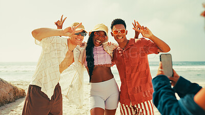 Buy stock photo Beach, friends and cellphone for picture, vacation and travel with tropical island, smile and peace sign. Ocean, people and group with smartphone, capture memory and excited with holiday and Zanzibar