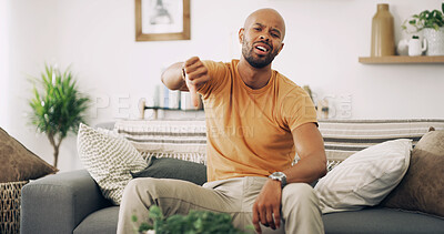 Buy stock photo Annoyed, portrait and thumbs down with man on sofa in living room of home for denial or rejection. Emoji, frustration and stress with unhappy person in apartment for reaction to bad news or negative