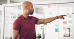 Planning, glass wall and man with sticky note, office and ideas for agenda, brainstorming and business. Presentation, media analyst and pointing for project, person and audience research for agency
