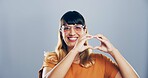 Happy woman, portrait and heart hands with glasses for love, care or romance on a gray studio background. Face, female person or romantic gesture with smile, icon or emoji for support on mockup space