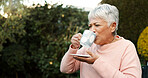 Nature, coffee and senior woman in garden for morning relax, peace and calm in backyard of home. Retirement, wellness and elderly female person drinking cappuccino outdoor at nursing facility.