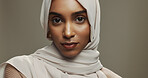 Serious, portrait and woman with hijab in studio for Eid celebration with traditional islamic scarf. Makeup, beauty and face of muslim female person with headscarf for ramadan by brown background.