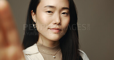 Buy stock photo Asian woman, portrait and selfie in studio with beauty, natural cosmetics or smile. Influencer, confident or POV on gray background for photography, social media engagement or makeup tutorial results