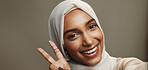 Studio, selfie and woman with peace sign, hijab and smile for social media, live streaming or profile picture. Space, portrait and confident face of muslim girl on grey background for happy Ramadan