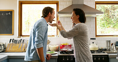 Buy stock photo Couple, cooking and feeding food in kitchen at house for organic ingredients, meal prep and healthy lunch. Woman, man and taste recipe for nutrition salad, vegan diet and romance for bonding together