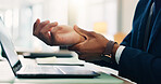 Business person, hands and laptop with wrist injury for carpel tunnel, bruise or overwored at office desk. Closeup, employee or muscle tension with fibromyalgia for joint inflammation, strain or ache