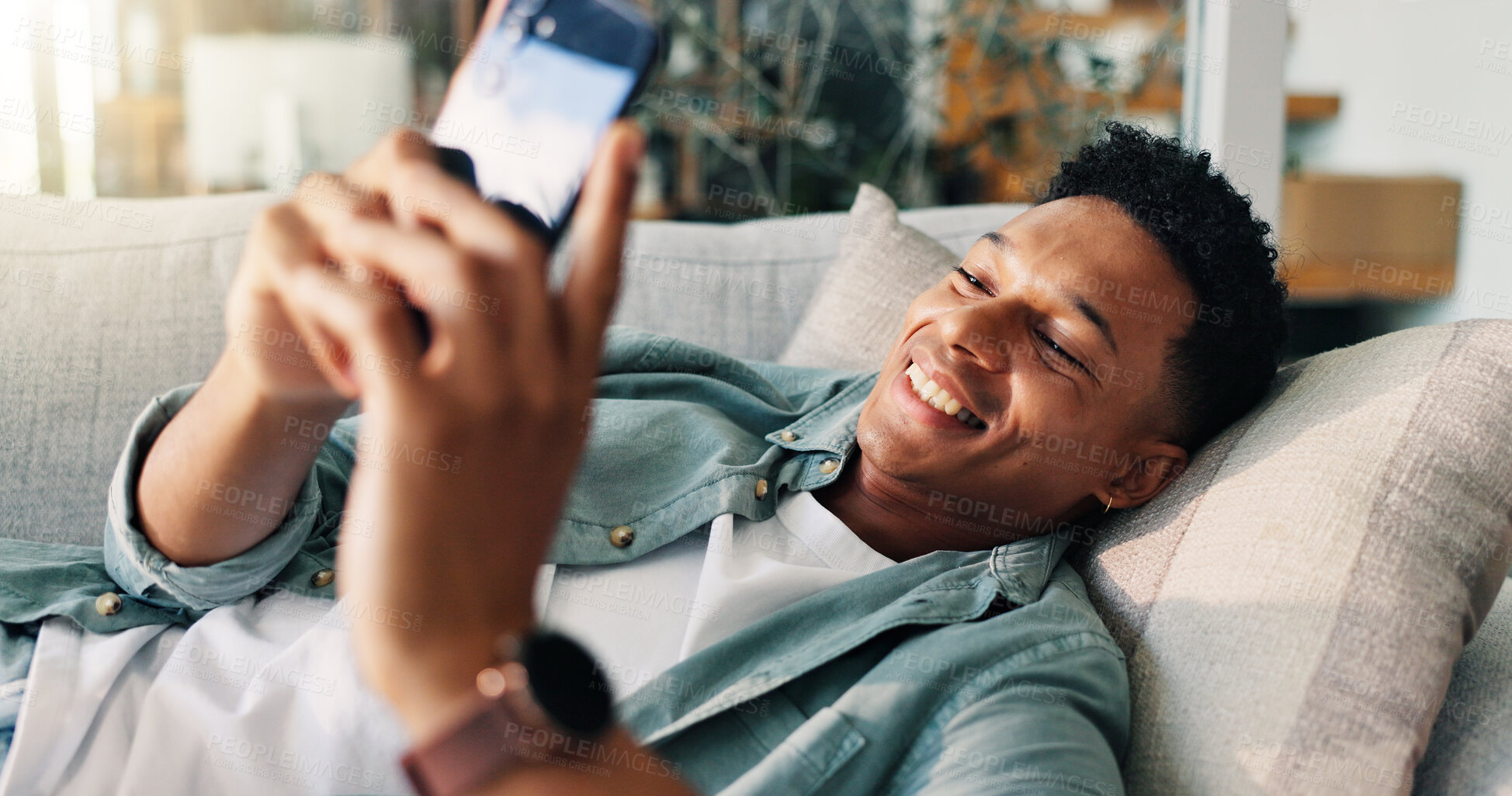 Buy stock photo Man, happy and relax with phone on sofa for weekend break, dating site chat or streaming service. Smile, person or resting with smartphone in home with online subscription, social media or web scroll