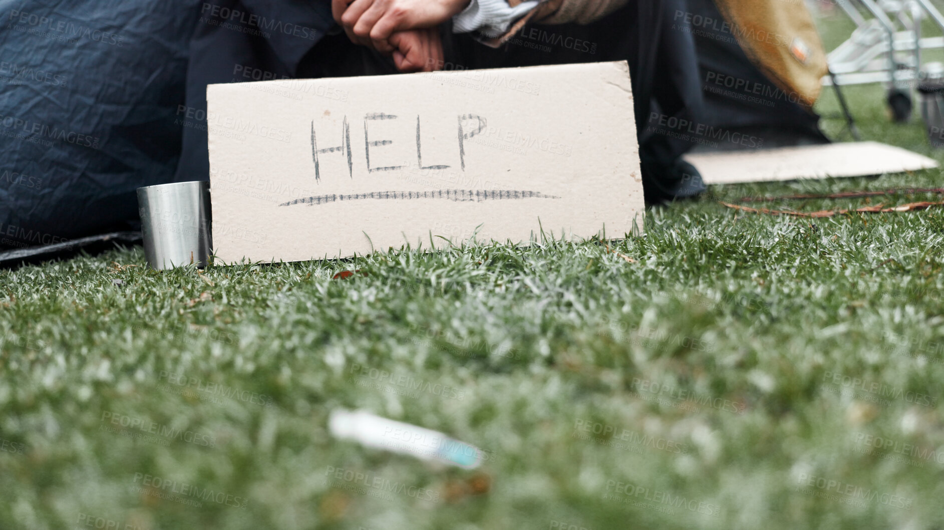 Buy stock photo Hands, homeless and sign for help with cup, poverty and begging for money with addiction to drugs at park. Person, outdoor and cardboard for donation, care and hope for support on ground in Brazil