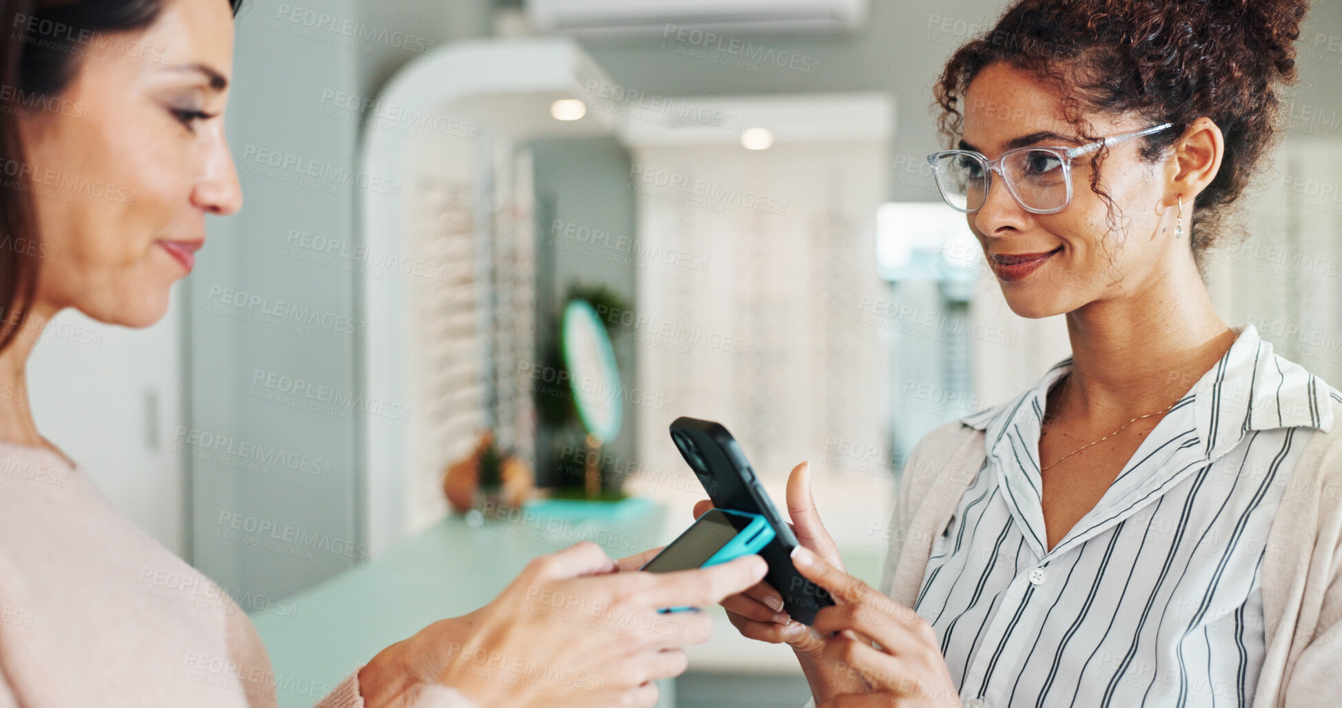 Buy stock photo Happy woman, customer and optometrist with pos machine for purchase or wireless transaction at optometry store. Female people, client and phone with mobile payment app for glasses, sight or vision