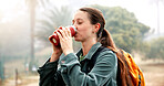Bottle, drinking water and hiking with woman outdoor in nature for adventure, hobby or journey. Break, hydration and vacation with thirsty hiker person in park for morning exploration or health
