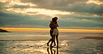 Couple, hug and happy at sunset, beach and bonding with love, care and water with clouds at dusk by sea. People, man and woman with embrace, smile and excited with connection on holiday by ocean