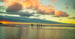Sunset, people running and friends at ocean for holiday, vacation and summer trip on island. Group, sea water and race by beach together for freedom, travel or energy for adventure at dusk with space