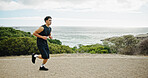 Seaside, running and man in street, training and wellness with cardio, workout and challenge. View, person and runner with exercise, outdoor and energy with practice, fitness and healthy with ocean