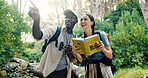 Pointing, travel and couple with birdwatching in forest, book for info and knowledge of species in nature. Binoculars, people and view with sightseeing, hiking and trekking with animal text in woods