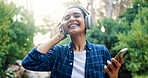 Happy woman, headphones and phone for music in forest, travel or adventure with energy for playlist. Smartphone, radio and listening to song in nature park, audio streaming and joy with tech outdoor